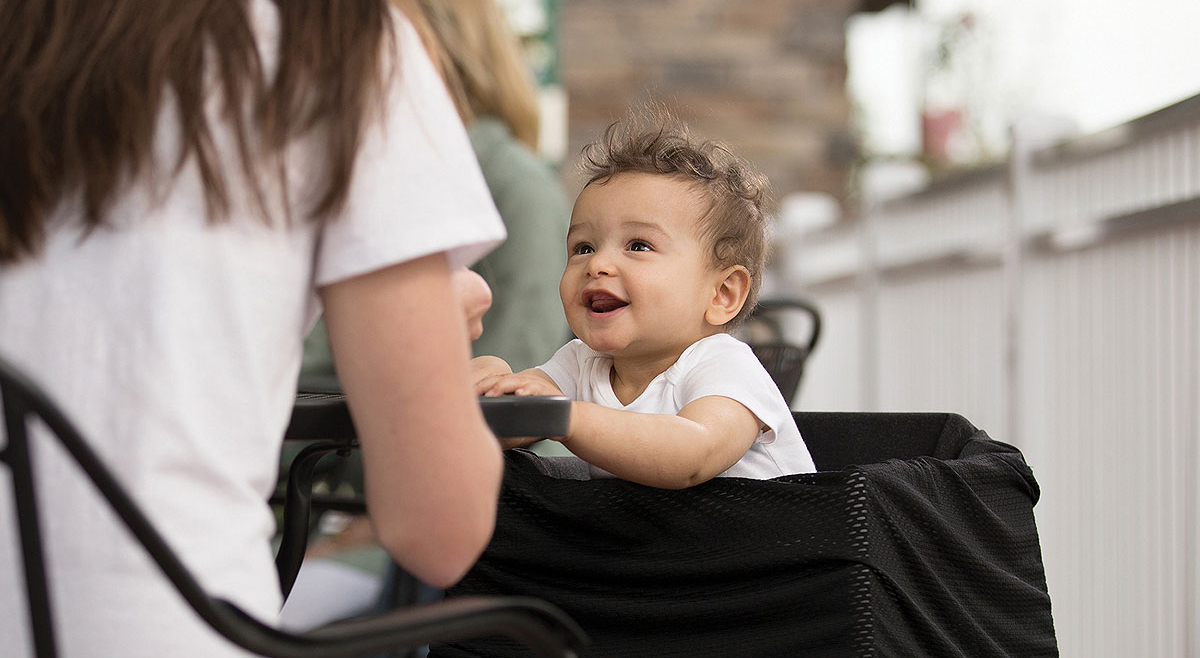 Happy baby sitting with mom at table outside