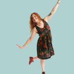 Dance Company Photoshoot with Rocky Mountain Rhythm featuring a dancer with red hair and shoes in a floral dress smiling.