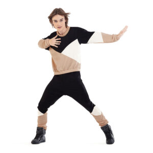 Hip hop dancer posed in a wide stance with one hand pressed to chest and one pressing away from body.