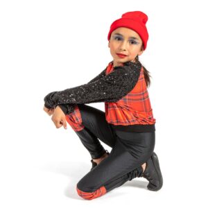 Hip hop dancer posed sitting on floor with hands propped over knee looking over their shoulder toward the camera.