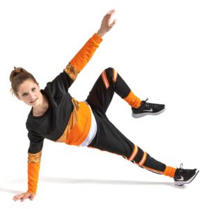 Hip hop dancer posed balancing on one leg as though in the middle of break dancing floor work. One arm is holding them up and the other reaching upward.