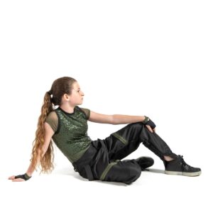 Hip hop dancer posed sitting on the floor with one foot propped up, leaning back on one arm with other draped over raised knee.