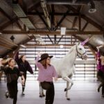 High end retouching composite of line dancers next to a unicorn in a barn.