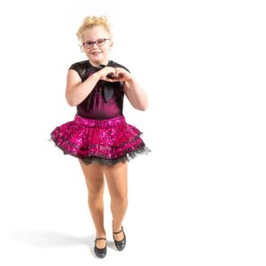 Young dancer posed with hands in the shape of a heart and one foot popped.