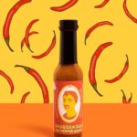 E-commerce product shot of Shaquanda's hot sauce with red pepper pattern illustrated behind it.