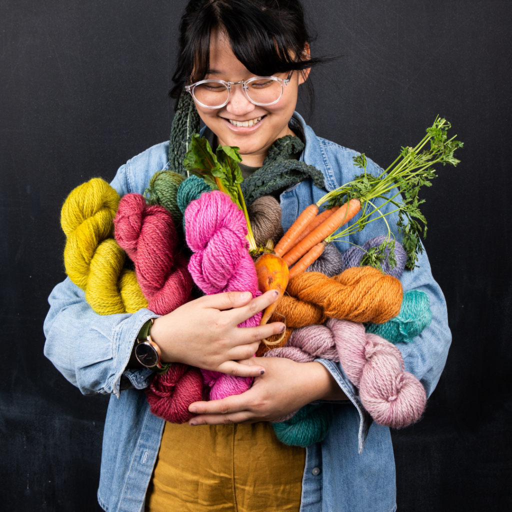 Fancy Tiger Crafts worker holding new line of yarns with vegetables that inspired their color.
