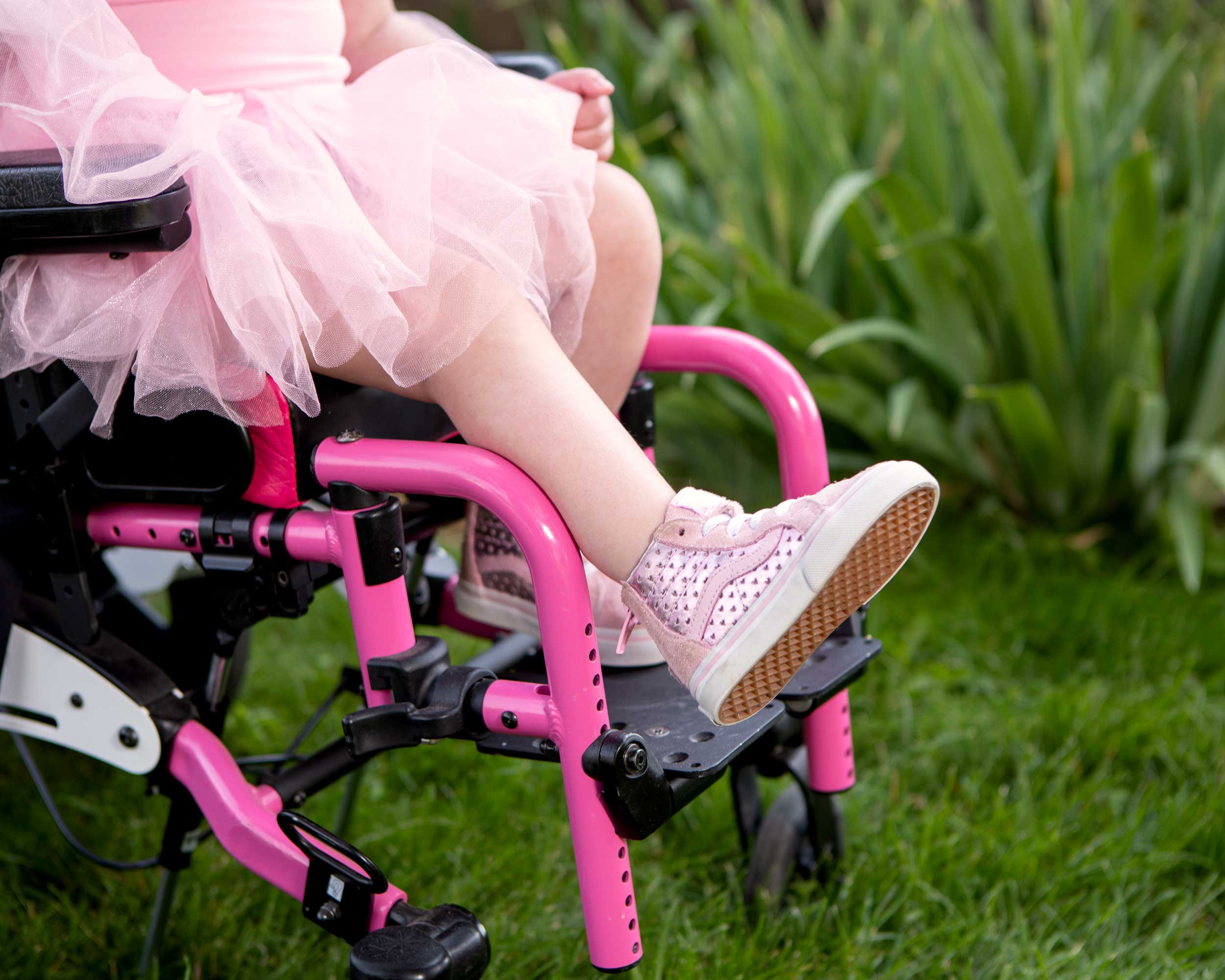 Young dancer in a tutu and pink wheelchair for brand photography.
