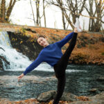 Dancer doing a let hold on a rock in front of a waterfall