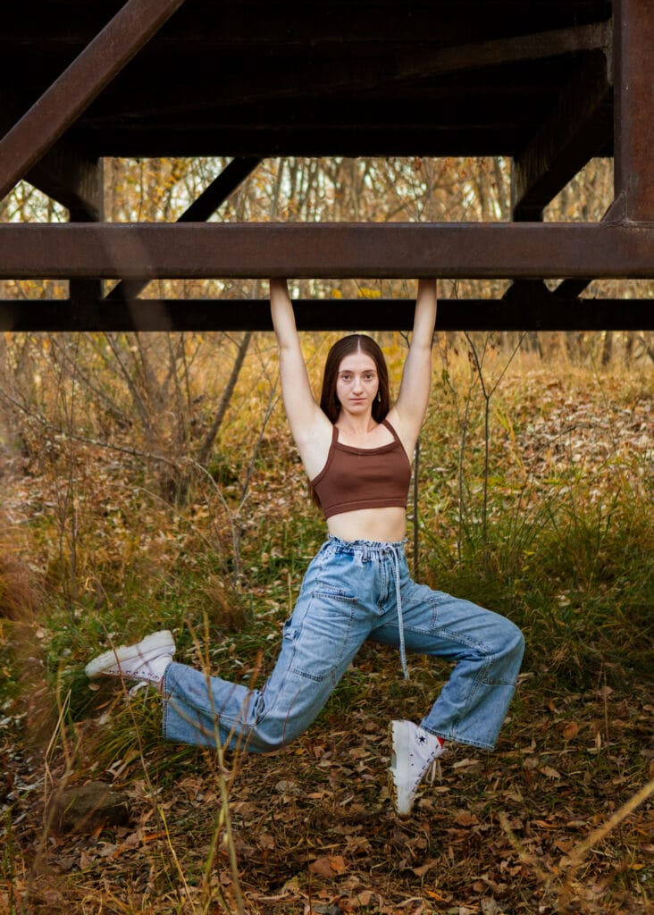 Dancer hanging off a bridge in a stag pose