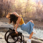 Dancer posed on her wheelchair pushing forward into a layout