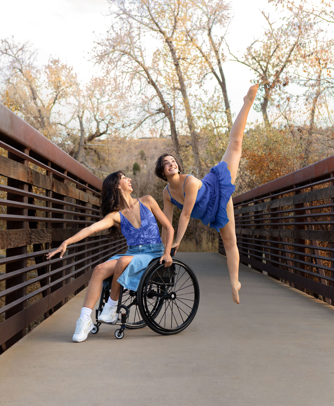 Dancing duet on a bridge, one in a wheelchair reaching out and the other leaping back