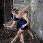 Dancers against a crumbling building posed wrapped around each other