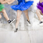 Dancers in brightly colored tutus and black converse leaping in the air