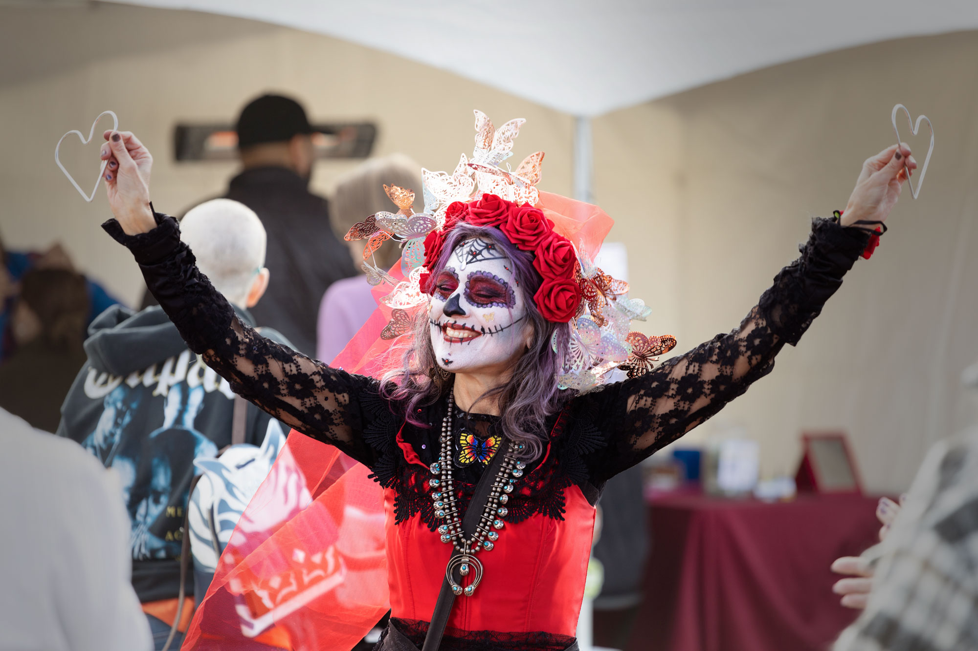 Magician with Dia De Los Muertos costume and makeup showing a trick