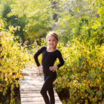 Young dancer posed on bridge with trees around