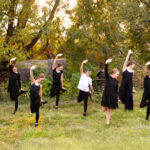 Dance team posed in front of trees in black outfits