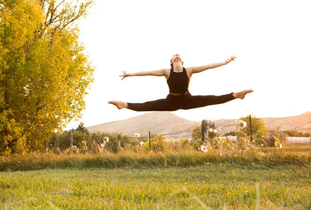 Dancer in a split leap with a mountain scape behind