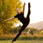 Dancer in a tilt leap with a mountain scape behind