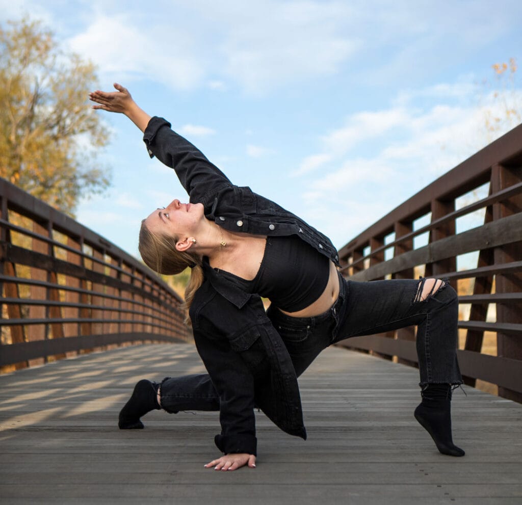 contemporary jazz dance company dancer posed on bridge in deep lunge reaching up to sky