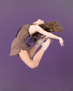 contemporary dancer posed in C jump on purple