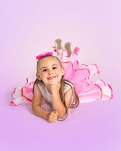 young ballet dancer posed on tummy with one hand under chin and feet kicked up