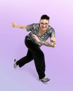 tap dancer posed in a split riff leaning forward and hands pressed to side on purple