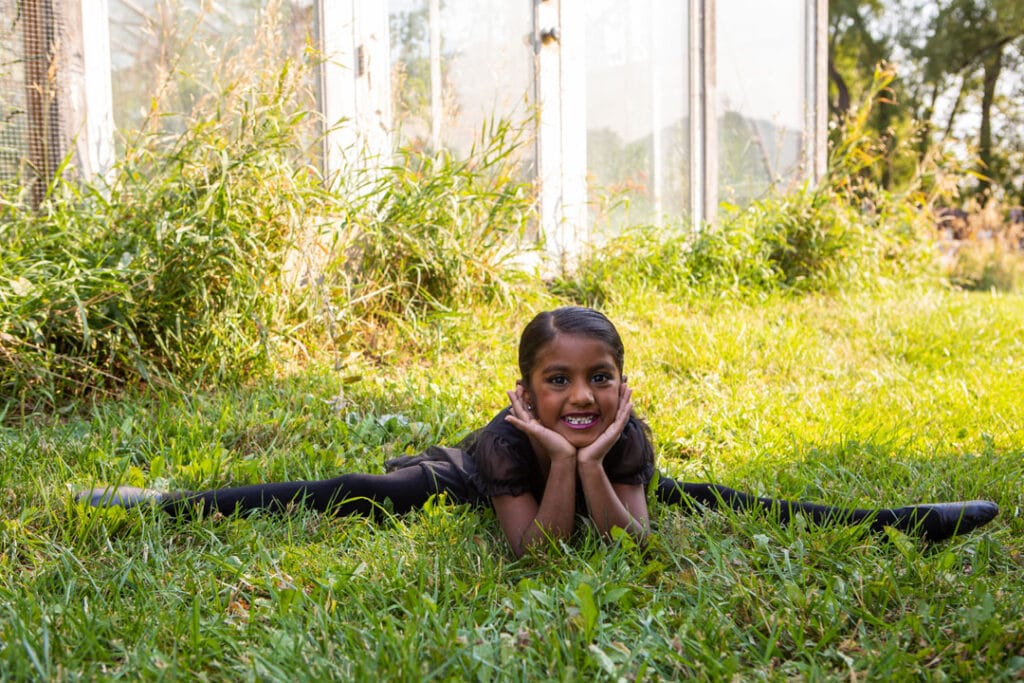 contemporary jazz dance company dancer posed in the grass in a split leaning on hands