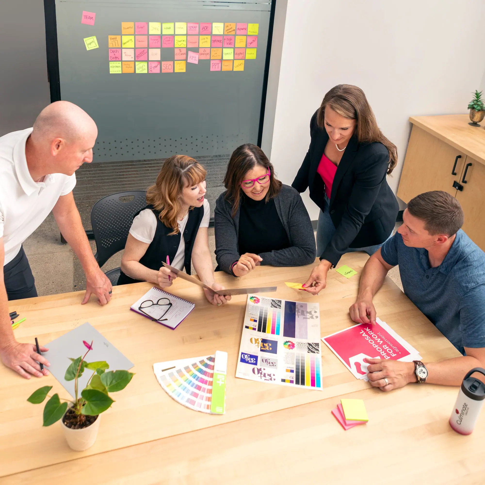 Creative team brainstorming marketing and branding strategies at a wooden table.
