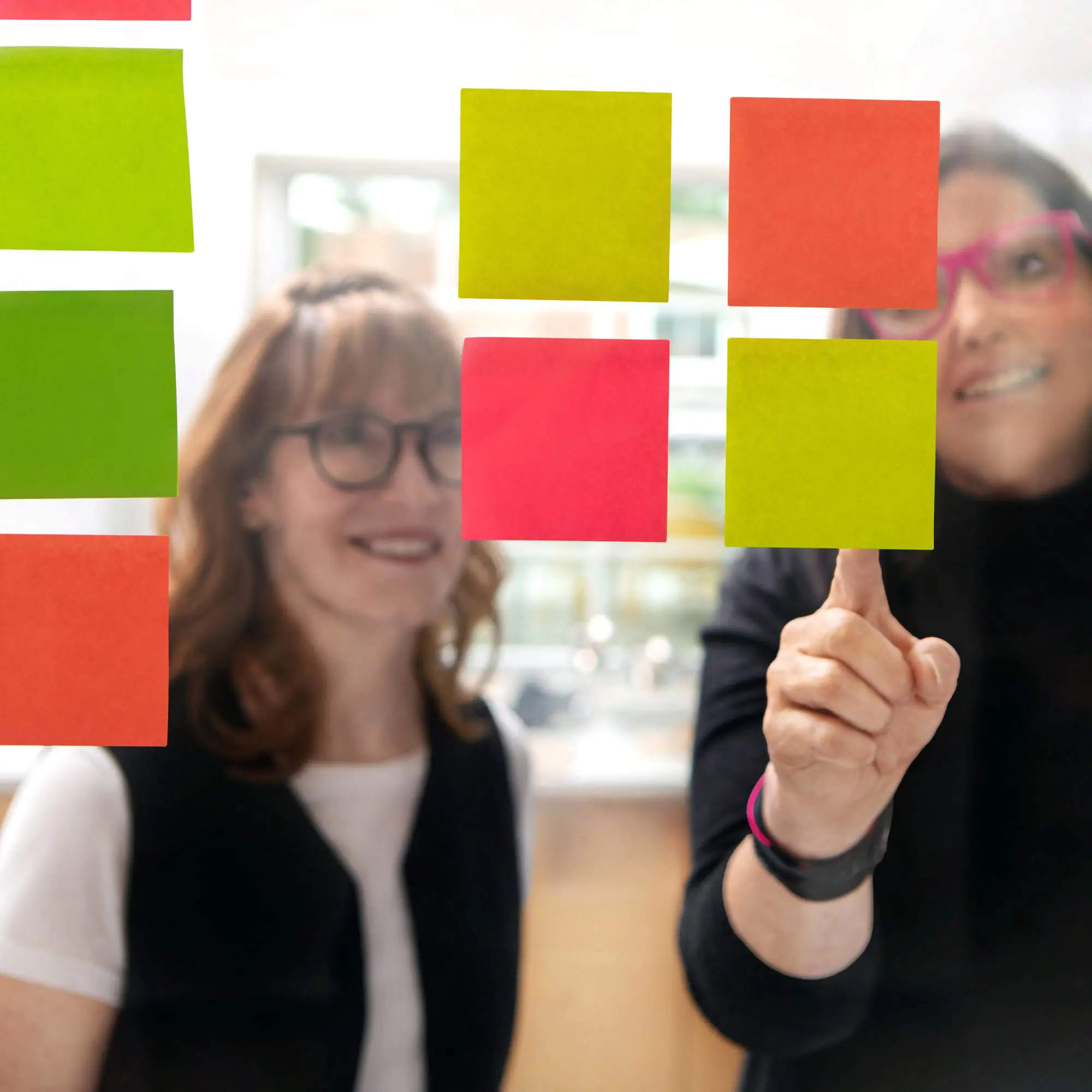 Colorful sticky notes on glass window with business team brainstorming at Andrews Artistry.