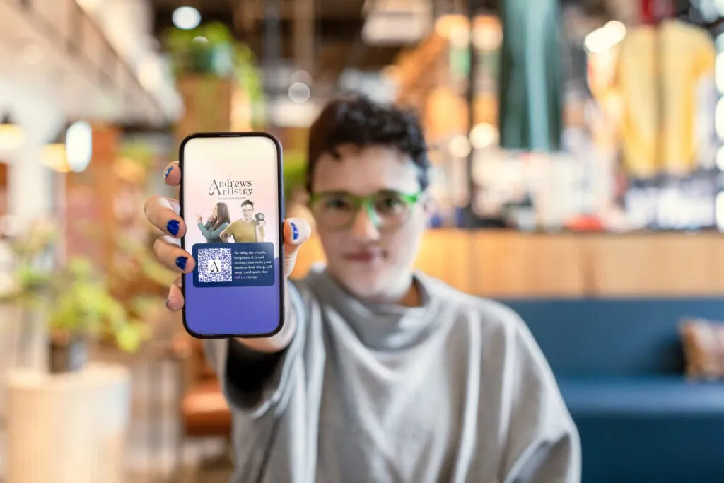 1. Young woman holding phone displaying Andrews Artistry logo, digital branding, vibrant colors.
