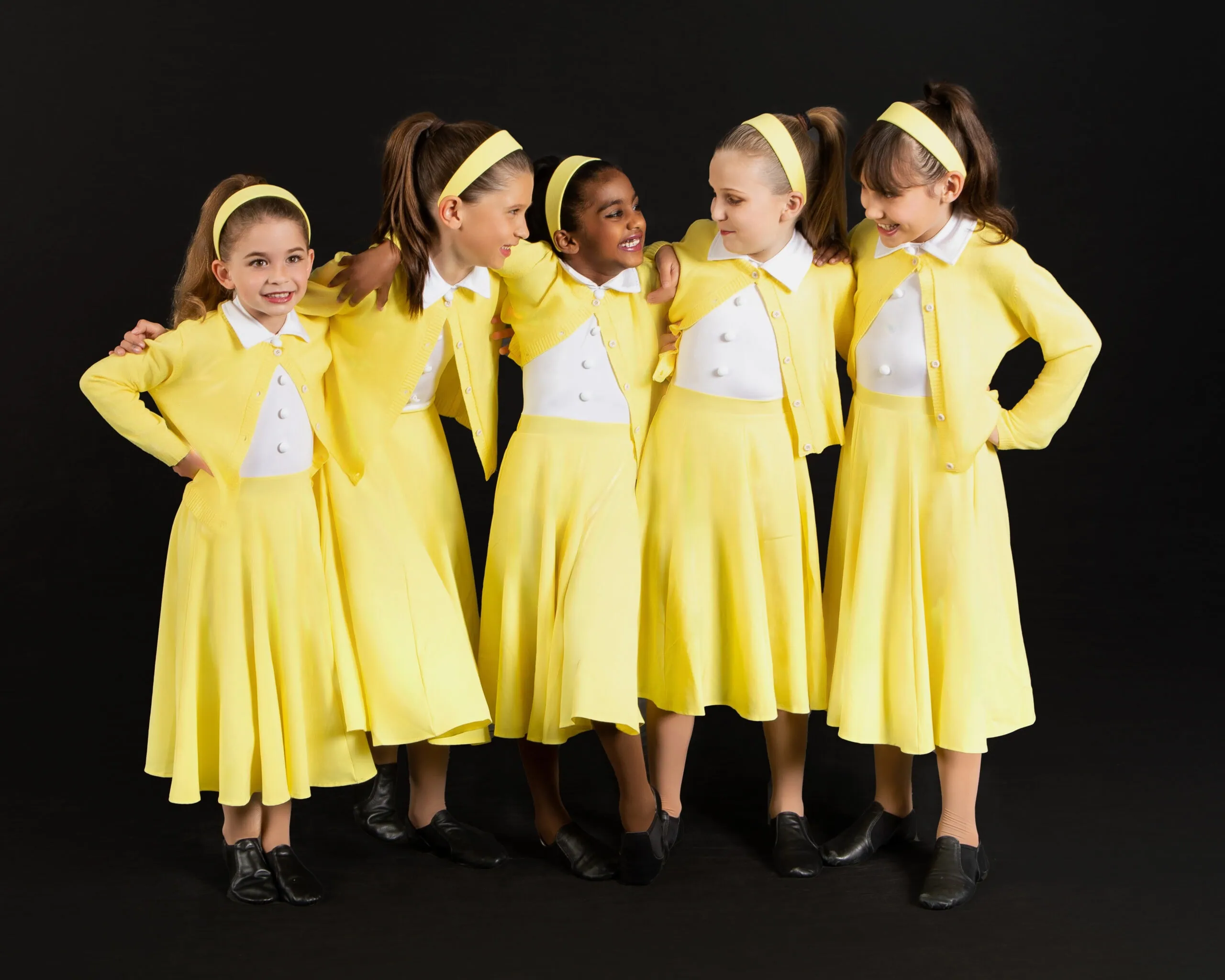 Girls in yellow dresses posing together.