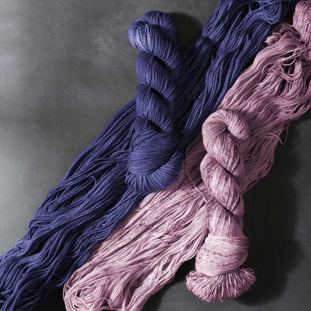 Bold purple and soft pink yarn skeins, perfect for luxury knitting and handmade jewelry projects.