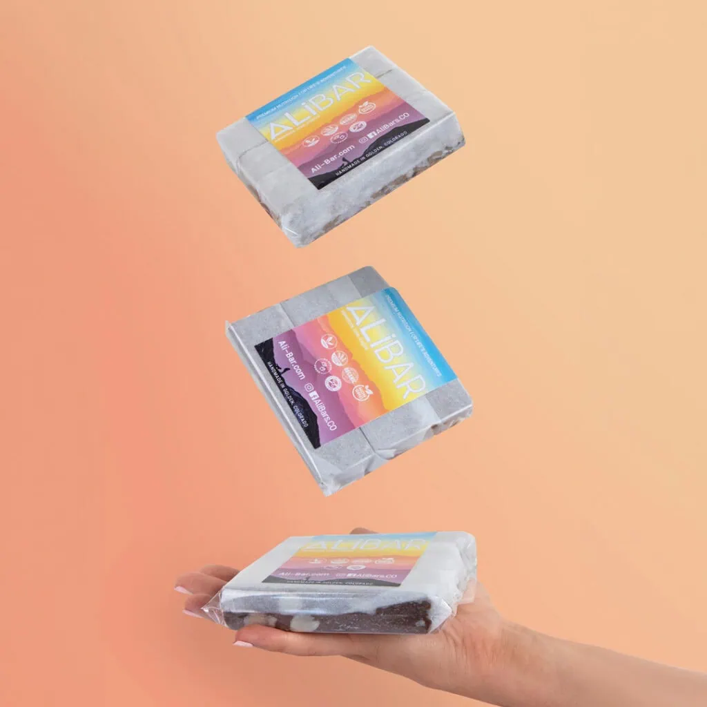 Hand holding natural soap bars with colorful Allibar packaging, eco-friendly skincare products.